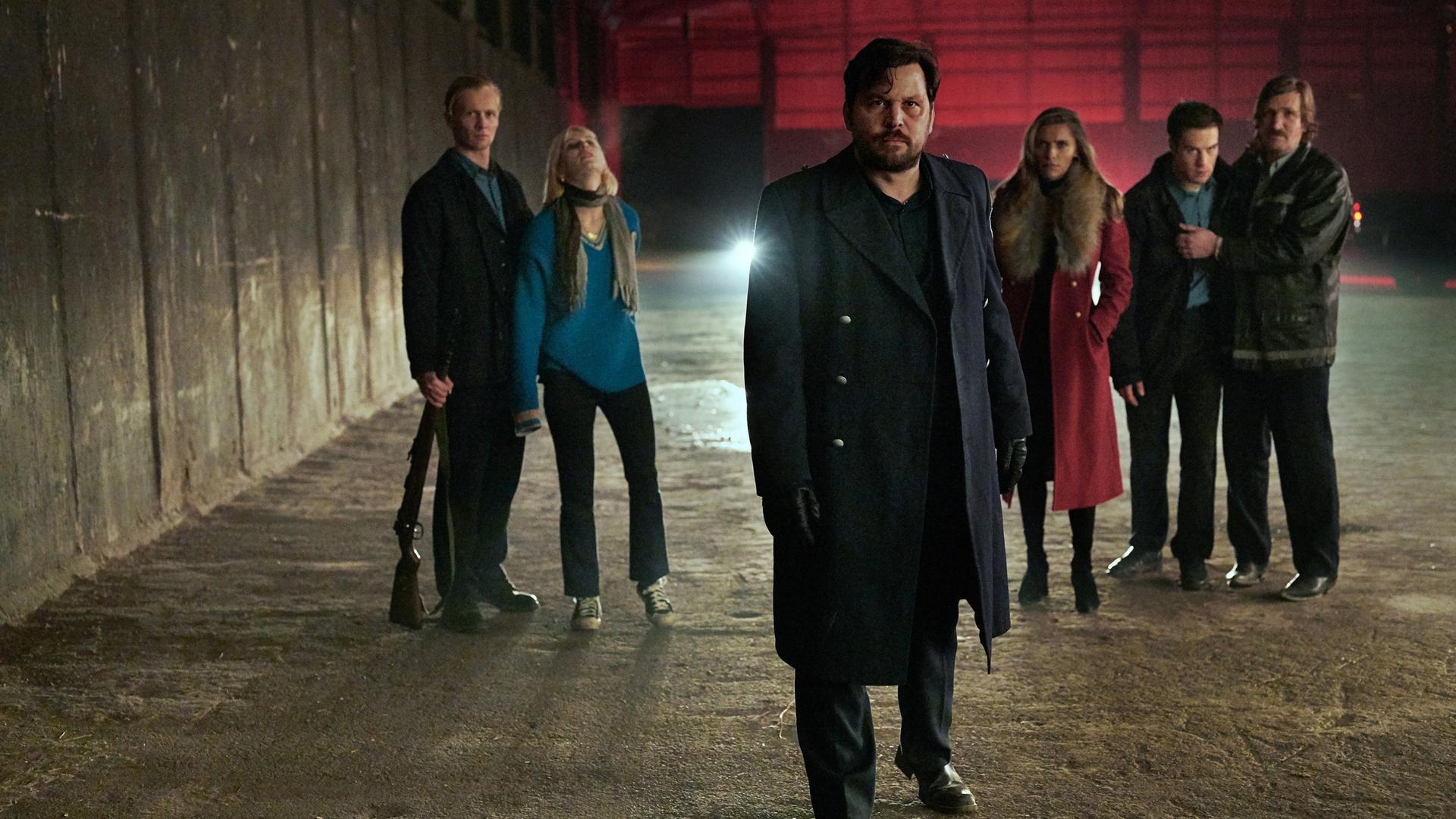 "Wir können nicht anders": Herrmann (Sascha Alexander Geršak) in leerstehender Fabrikhalle mit Thoralf (Roman Schomburg), der Edda (Alli Neumann) festhält, links hinter ihm und Katja (Sophia Thomalla), Ronny (Malte Thomsen) und Norbert (Karsten Mielke) rechts hinter ihm.