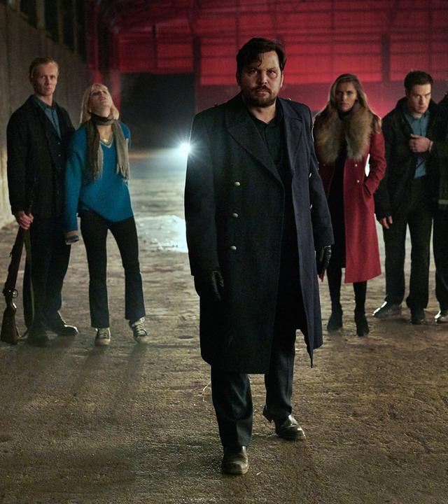 "Wir können nicht anders": Herrmann (Sascha Alexander Geršak) in leerstehender Fabrikhalle mit Thoralf (Roman Schomburg), der Edda (Alli Neumann) festhält, links hinter ihm und Katja (Sophia Thomalla), Ronny (Malte Thomsen) und Norbert (Karsten Mielke) rechts hinter ihm.