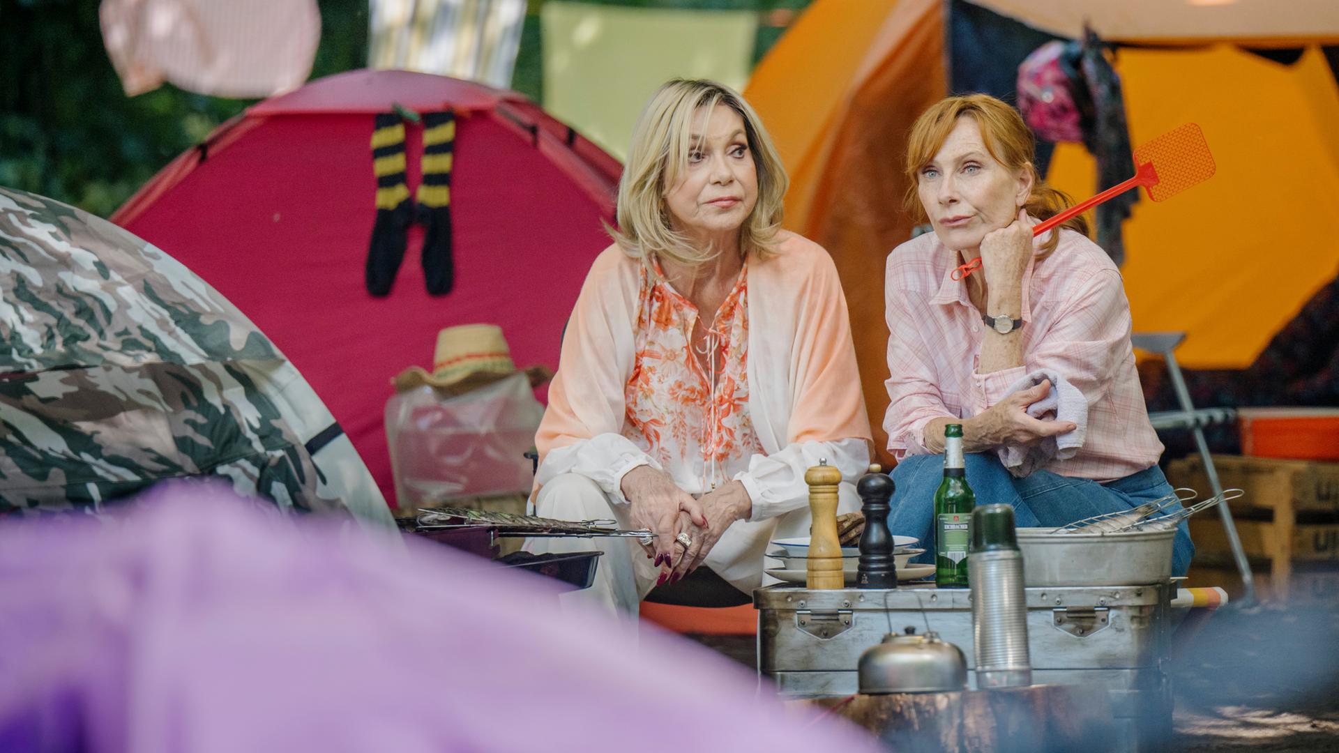 "Familie Bundschuh - Wir machen Camping": Susanne (Judy Winter, li) und Gundula (Andrea Sawatzki, re) sitzen zwischen Zelten und vor einem Grill und führen ein ernstes Gespräch.