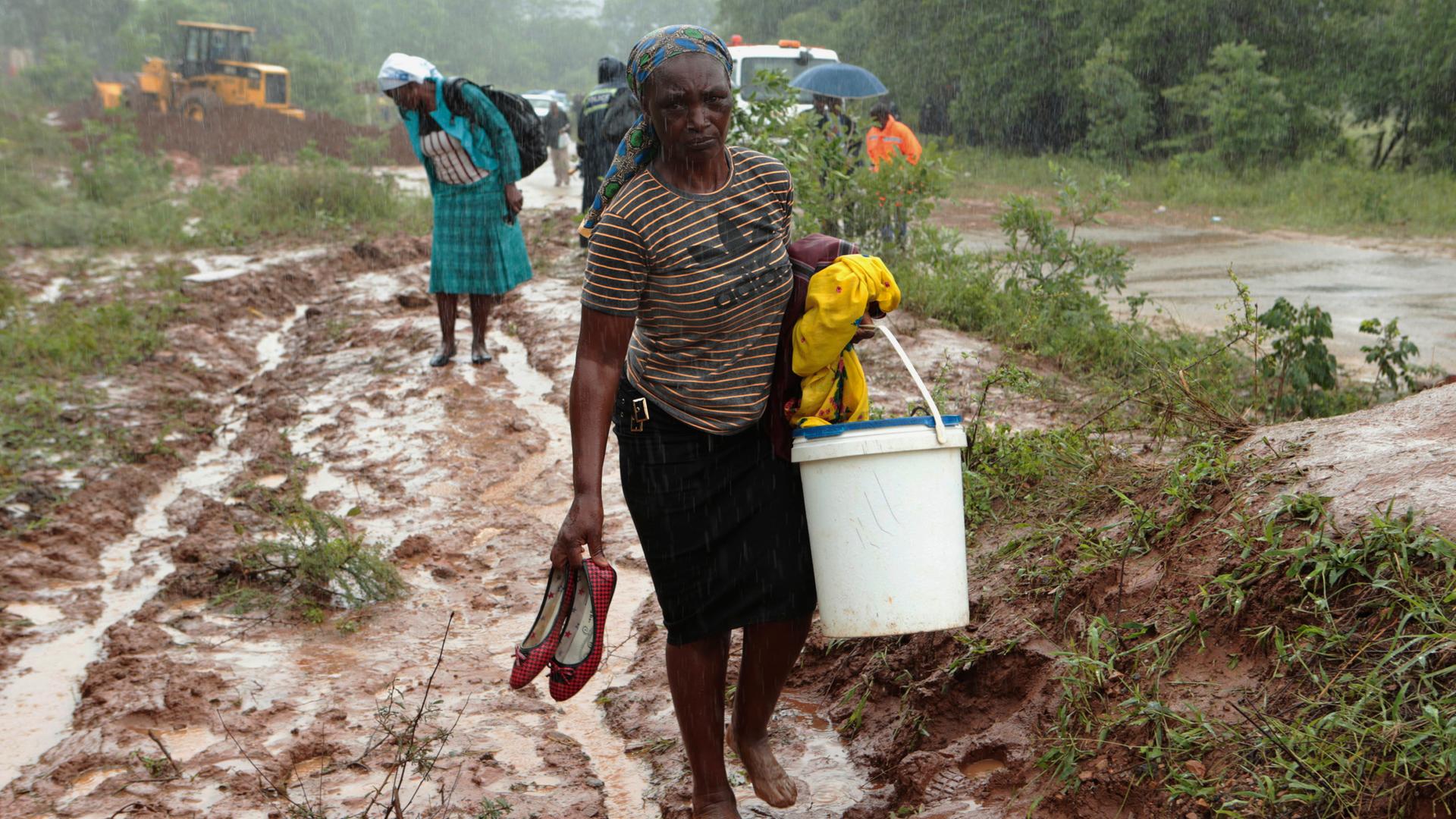 Frauen waten durch den Schlamm. Sie tragen ihre Habseligkeiten, Chimanimani, 18.03.19
