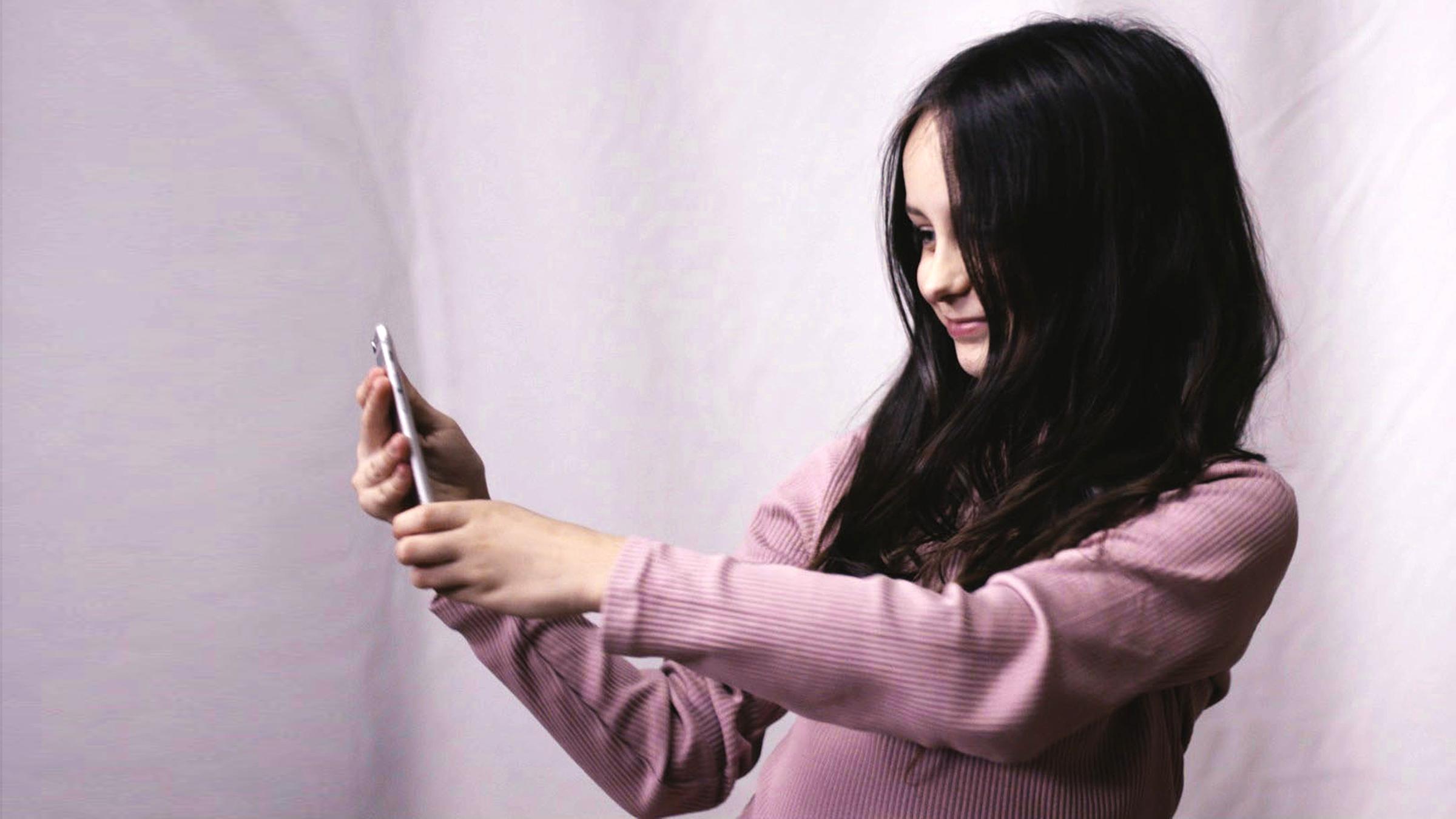 Symbolbild: Die neunjährige Ruby steht vor einer Leinwand und macht ein Selfie-Foto.