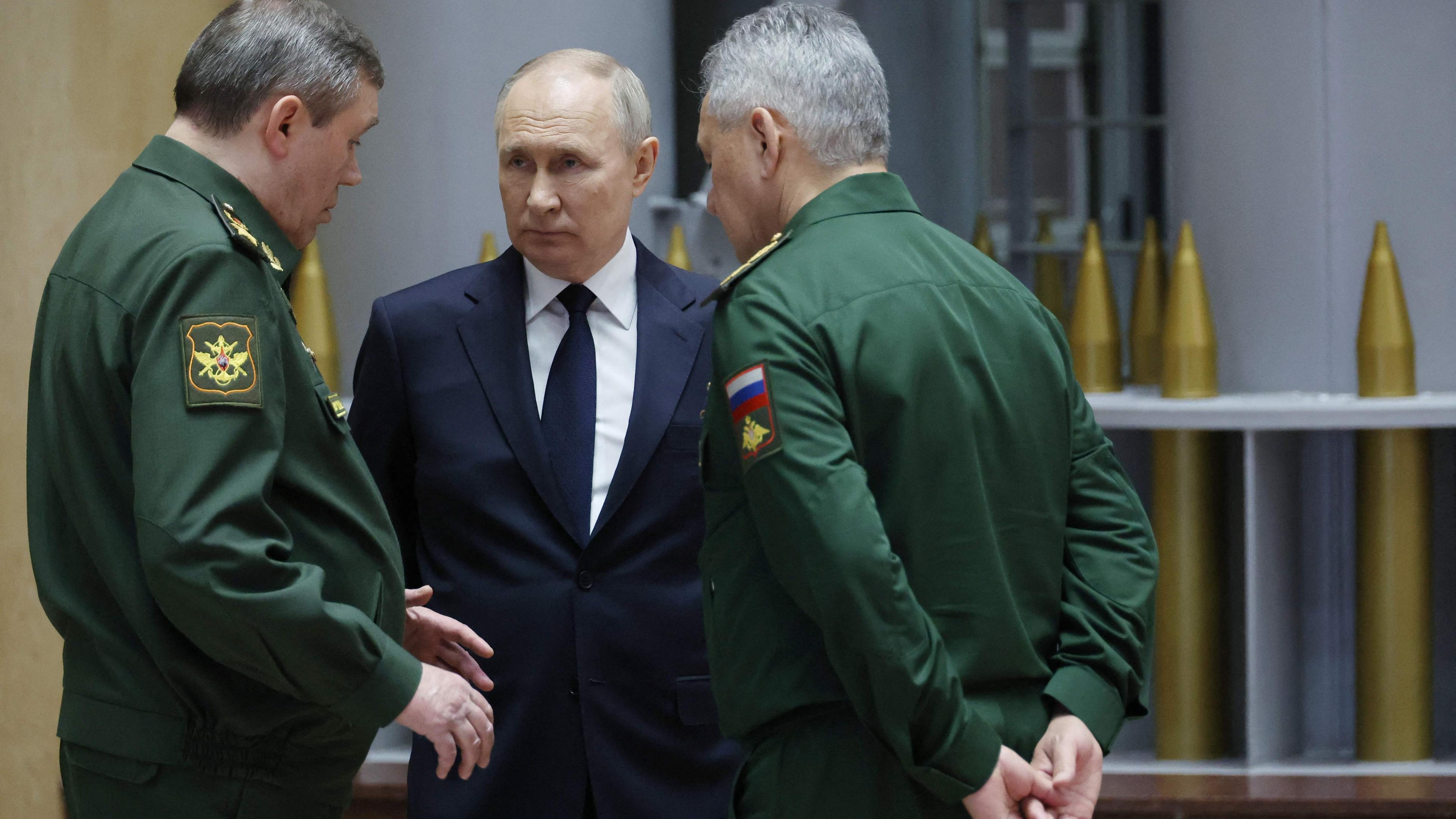 Das Bild zeigt den russischen Präsidenten Wladimir Putin (M.) im Gespräch, unter anderem mit Verteidigungsminister Sergej Schoigu.