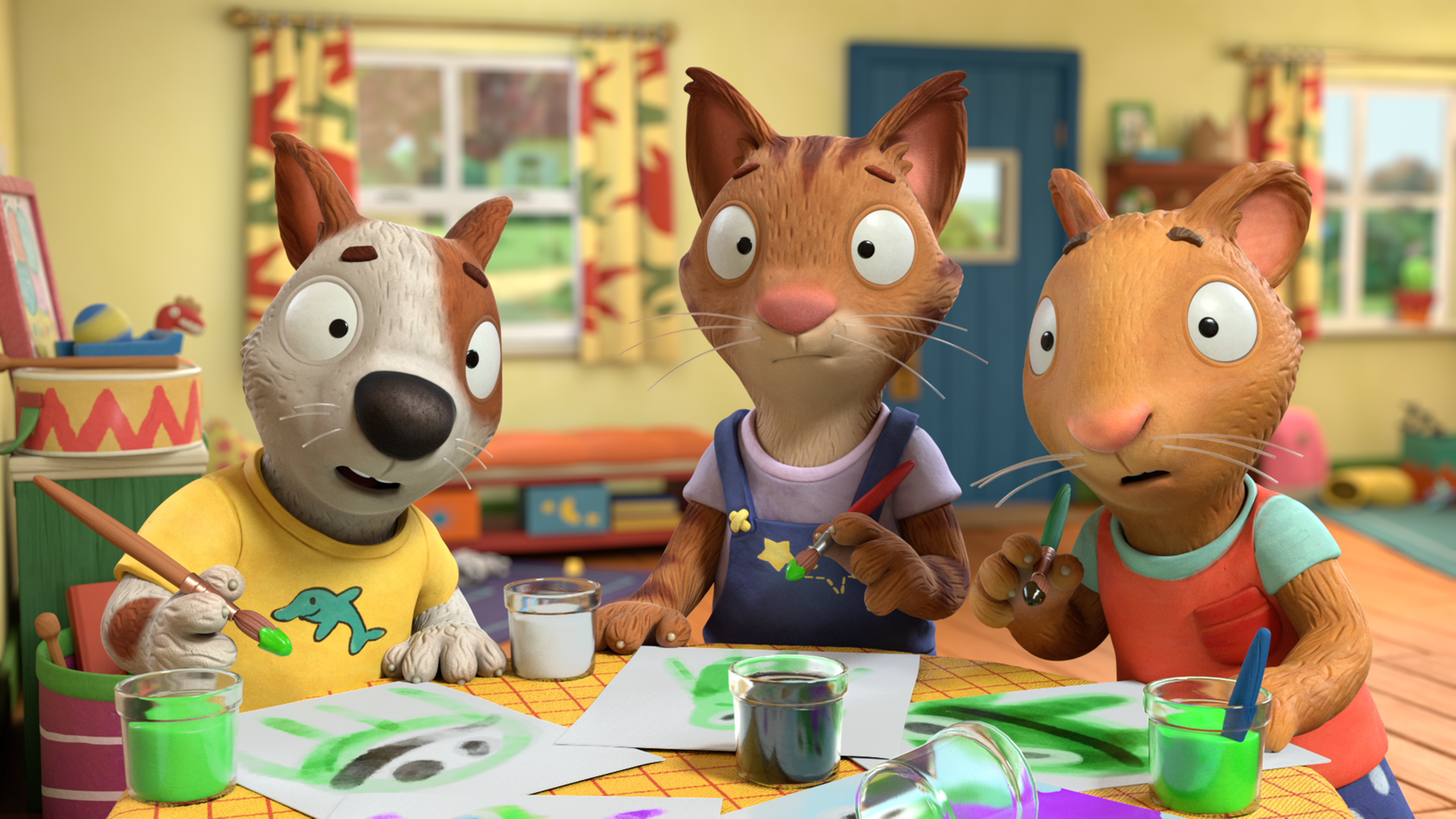 Zac, Frankie und Posy malen mit Pinseln und grüner Farbe Plakate.