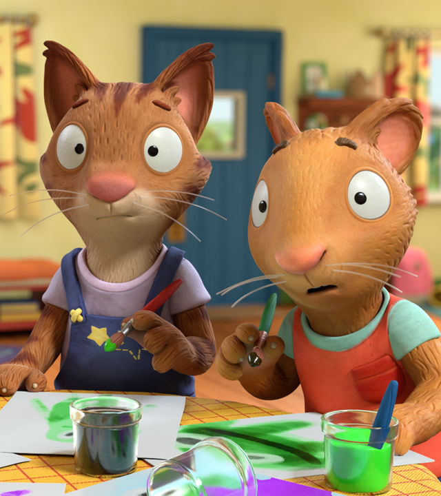 Zac, Frankie und Posy malen mit Pinseln und grüner Farbe Plakate.