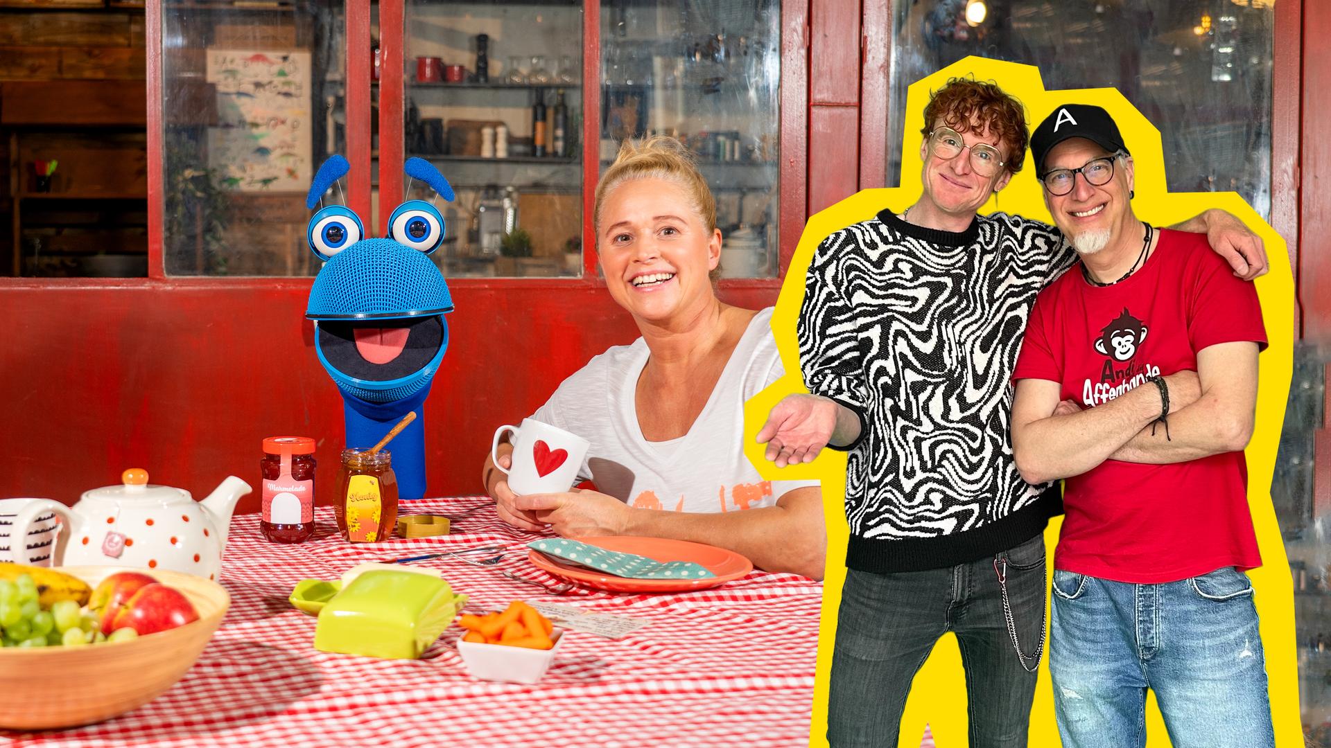 Singding (l.) und Singa (r.) sitzen am gedeckten Frühstückstisch. Im rechten Bildrand stehen Tommie von OK Tilda und Andi von Andi und die Affenbande.