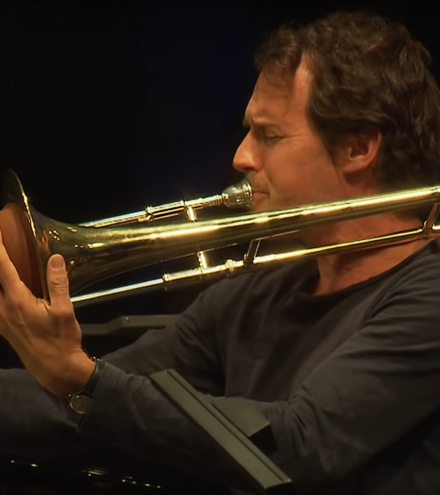Posaunist Nils Wogram seitlich, beim Spielen aufgenommen.