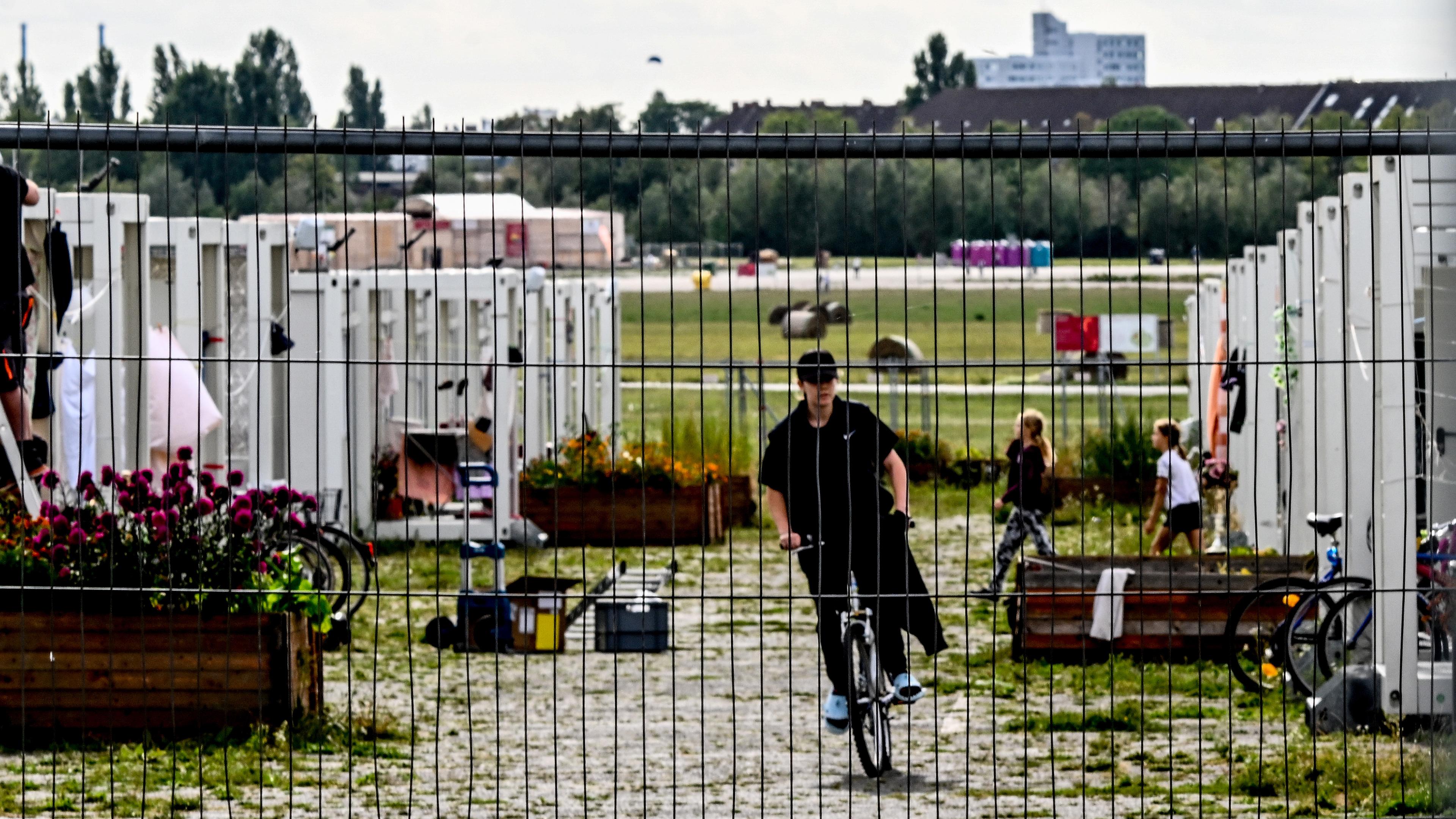 Flüchtlinge vor Containern, die als Flüchtlingsunterkünfte genutzt werden, am ehemaligen Flughafen Berlin-Tempelhof in Berlin