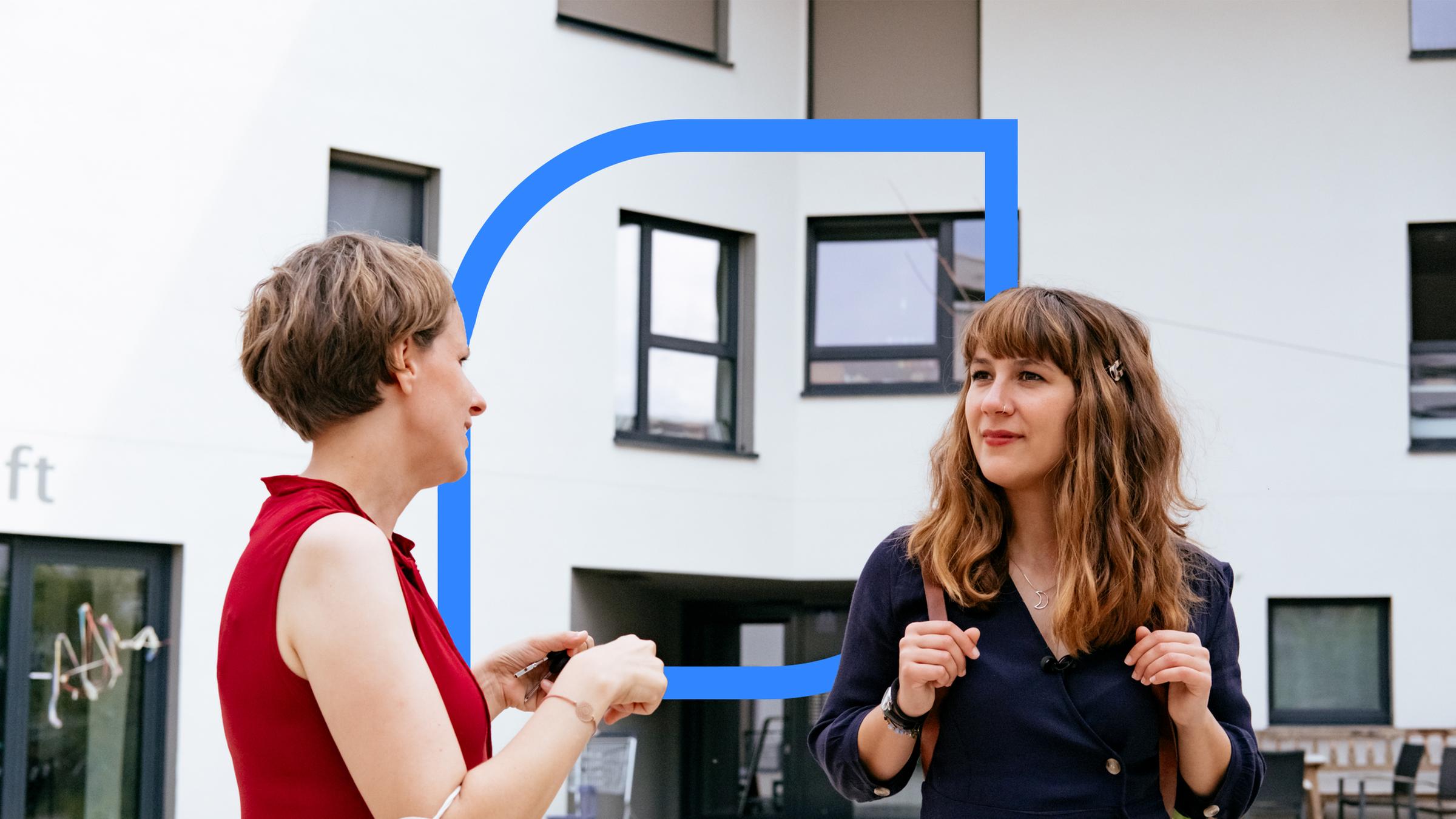 Zwei Frauen stehen vor einem Neubaugebäude.