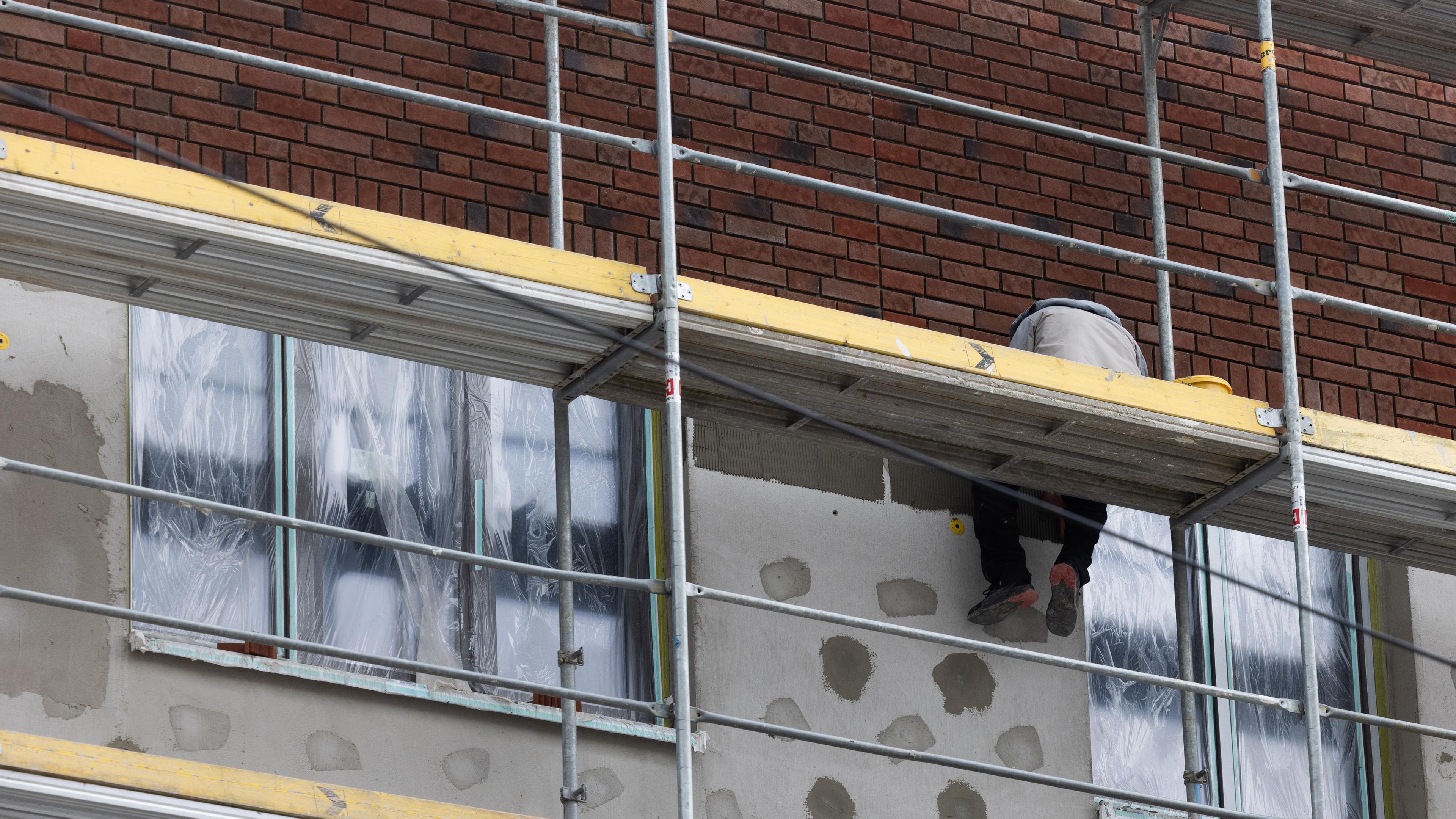 Klinkerriemchen werden auf die gedämmte Außenfassade eines Rohbaus (kfw55) für Mietwohnungen im Stadtteil Ehrenfeld aufgebracht.