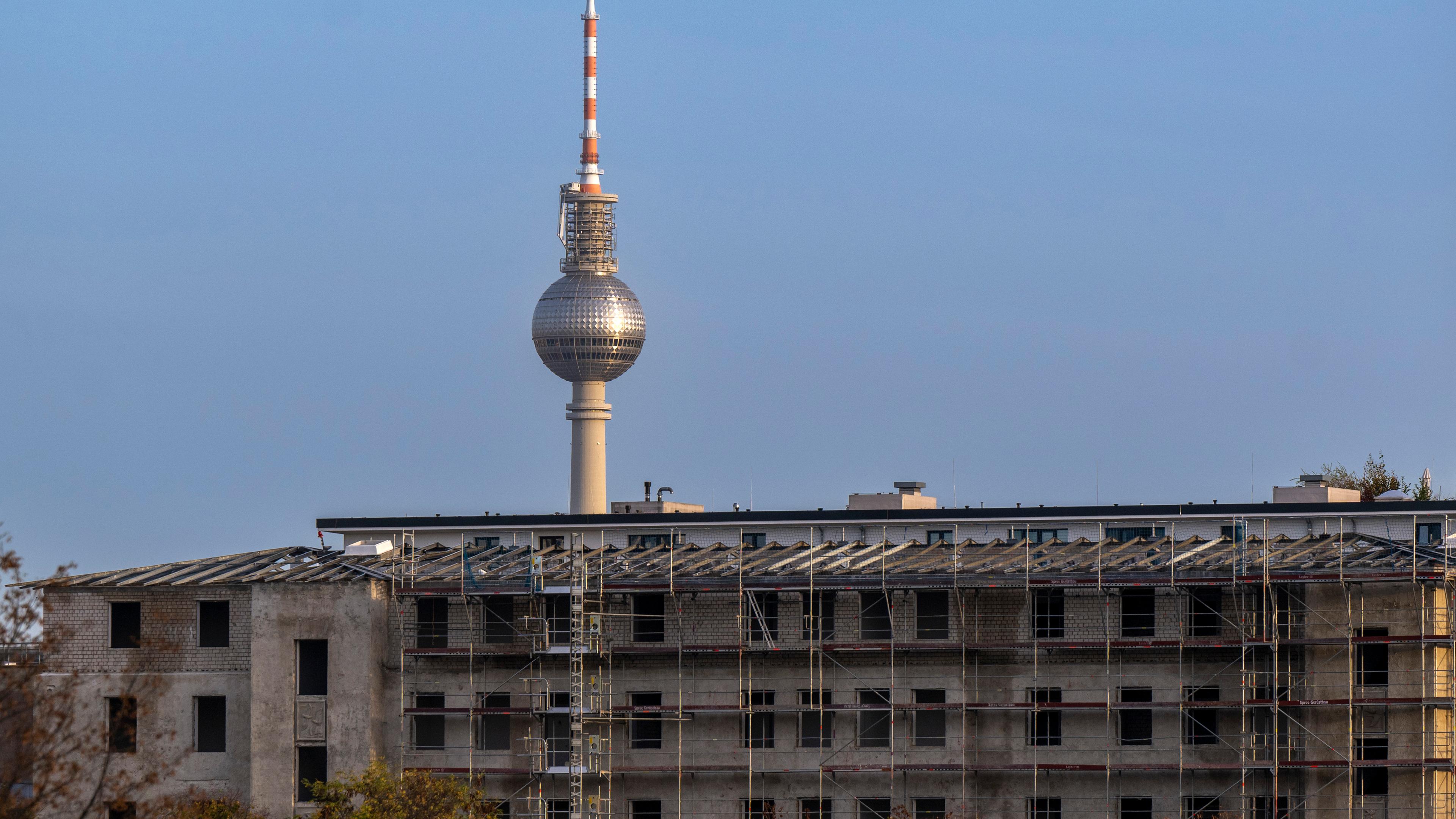  Ein Baugerüst steht an der Fassade von einem Rohbau vor der Kulisse des Berliner Fernsehturms. 