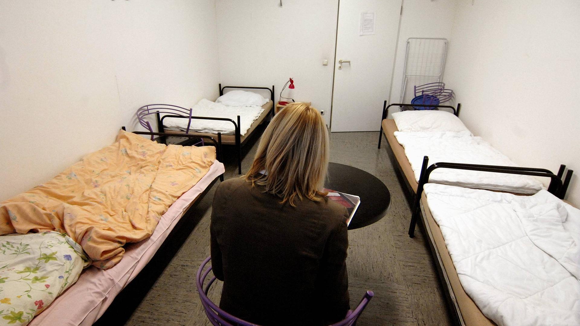 Frau sitzt in einem Zimmer in einer Notunterkunft