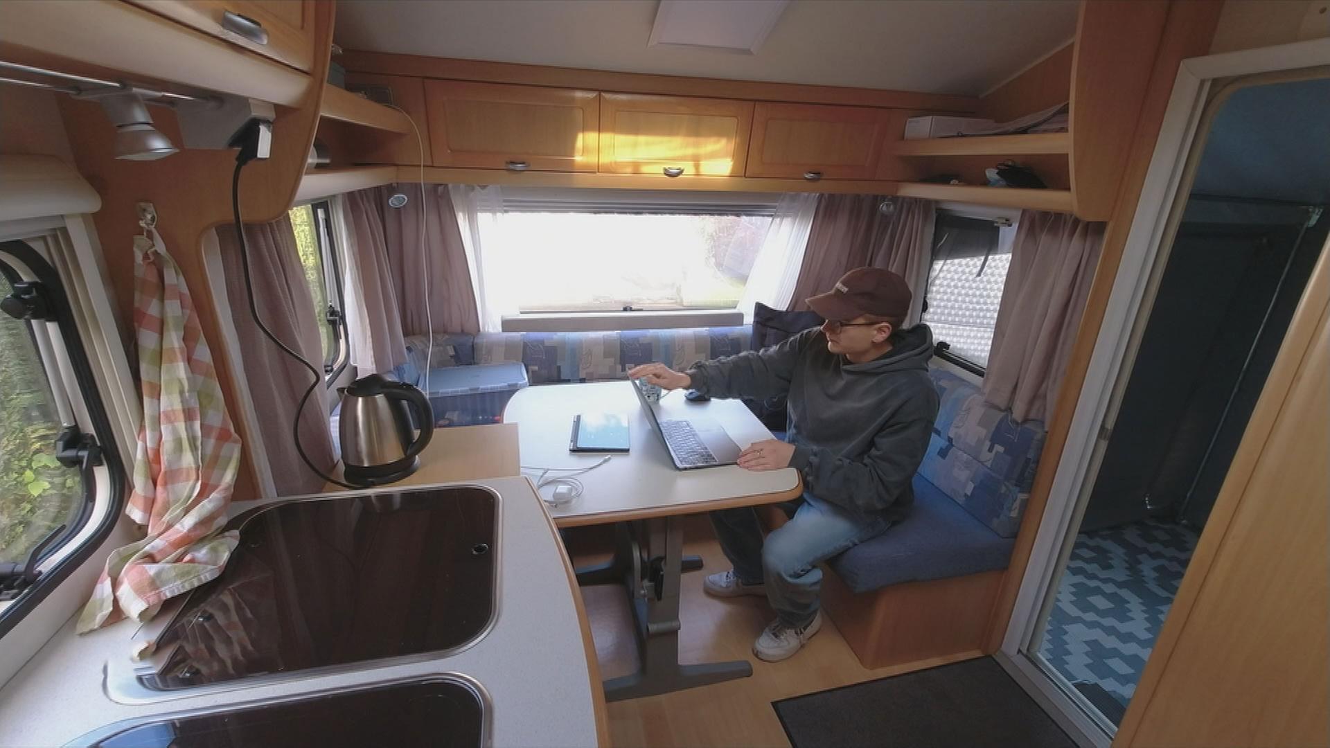Ein Student sitzt in seinem Wohnwagen.