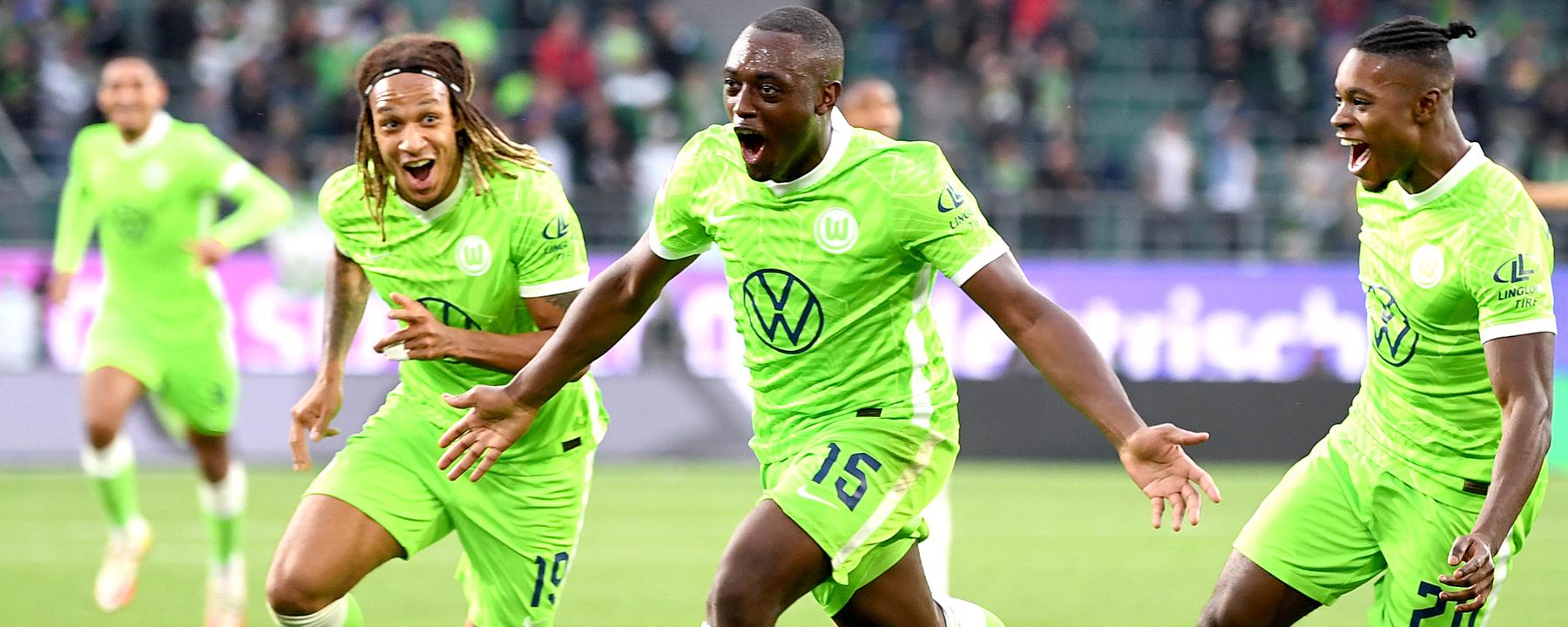 29.08.2021, Niedersachsen, Wolfsburg: Fußball: Bundesliga, VfL Wolfsburg - RB Leipzig, 3. Spieltag, in der Volkswagen Arena. Wolfsburgs Jerome Roussillon (M) jubelt nach seinem Treffer zum 1:0 mit seinen Teamkollegen Wolfsburgs Kevin Mbabu (l) und Wolfsburgs Ridle Baku (r). 