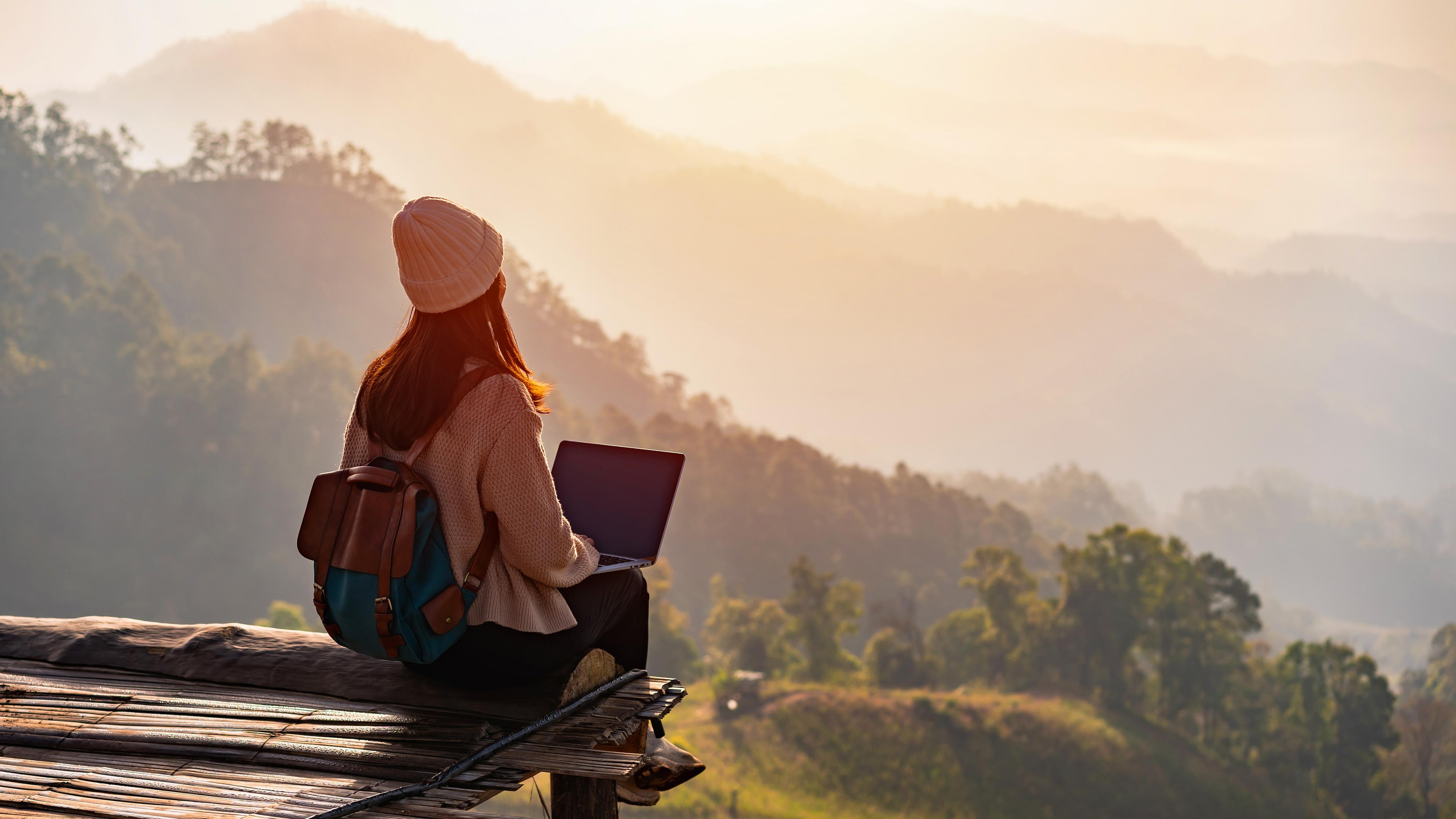 Eine Reisende arbeiten online mit Laptop und genießen die schöne Naturlandschaft mit Blick auf die Berge, aufgenommen am 26.09.2022