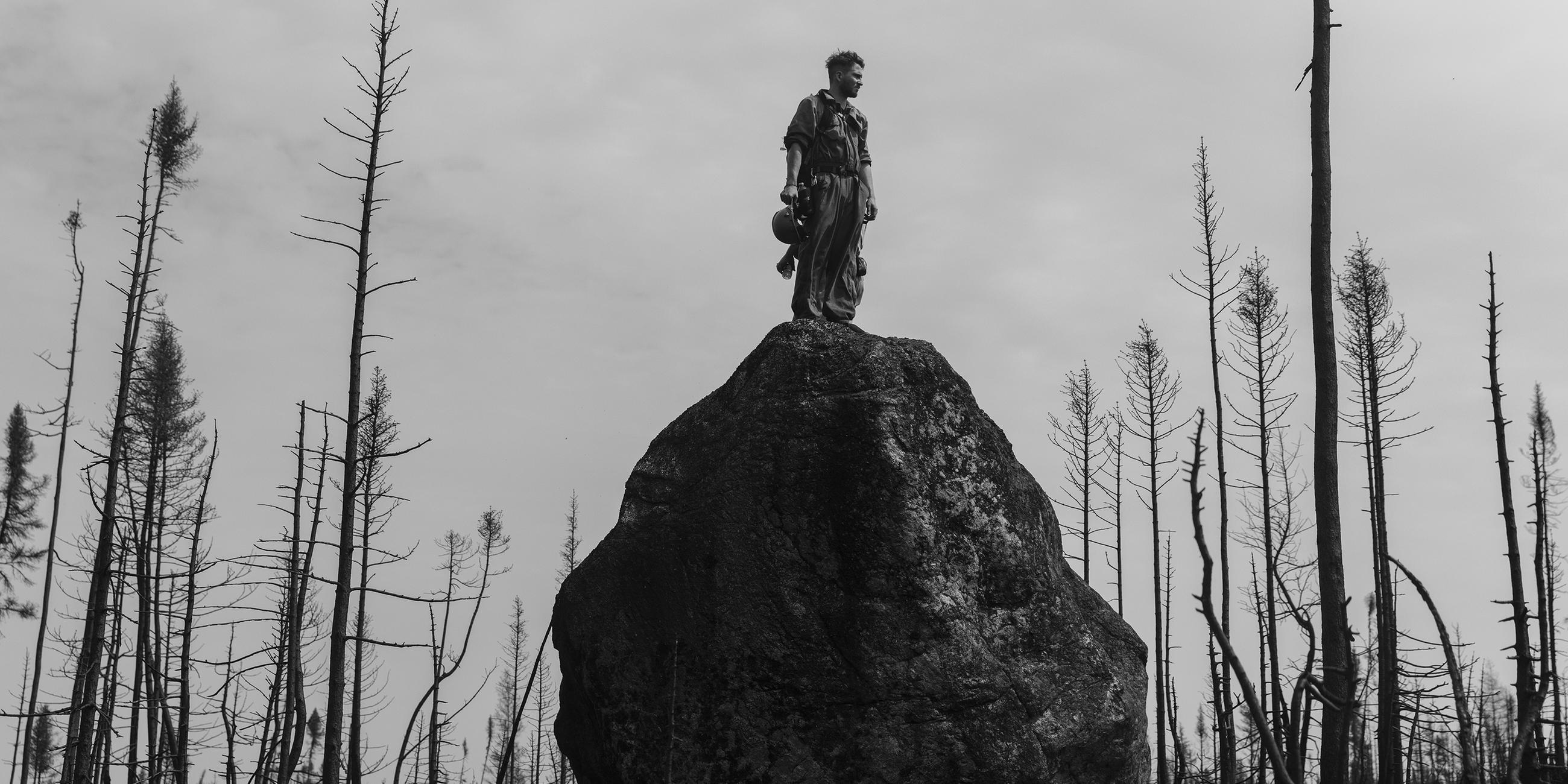 Theo Dagnaud steht auf einem Felsbrocken und blickt in den abgebrannten Wald in Quebec, Kanada (13. Juli 2023)