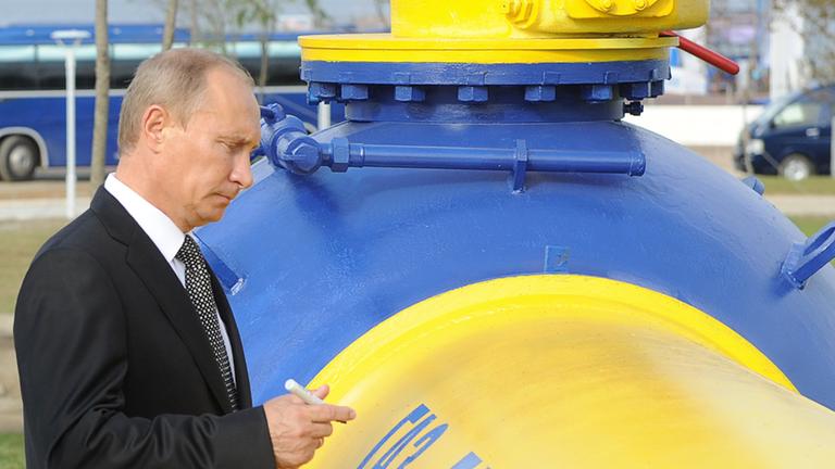 Präsident Wladimir Putin unterschreibt bei der Eröffnungsfeier einer neuen Gas-Pipeline auf einer gelb-blauen Stahlröhre.