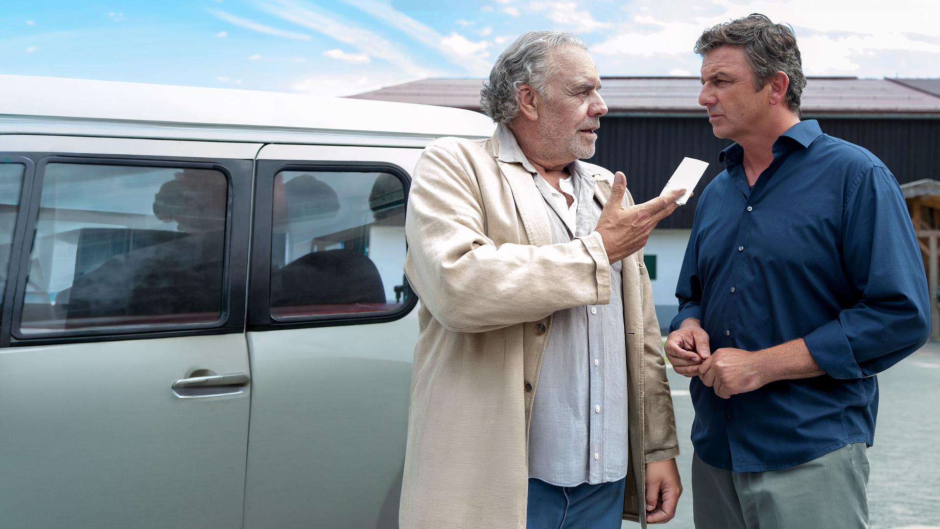 Ludwig (Christian Kohlund), der einen Zettel in der Hand hält, steht neben seinem Neffen Martin Gruber (Hans Sigl) vor dem Haus.