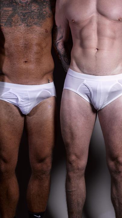Vier Männer mit unterschiedlichen Hautfarben stehen in einer Reihe. Sie tragen nur weiße Unterhosen. Ihre Köpfe und Füße sind nicht im Bild.