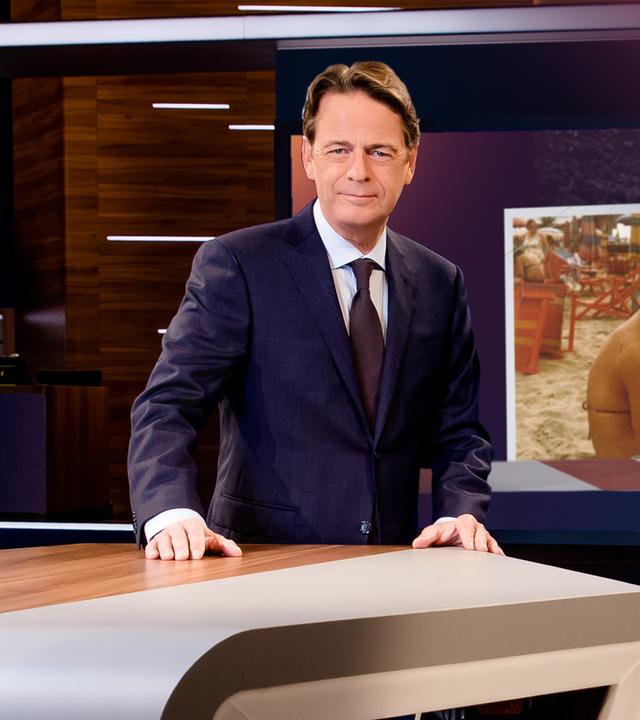 "Aktenzeichen XY... Ungelöst vom 21. Januar 2026": Rudi Cerne steht im Studio, im Hintergrund ein Bildschirm, auf dem ein Fall der Sendung abgebildet ist.