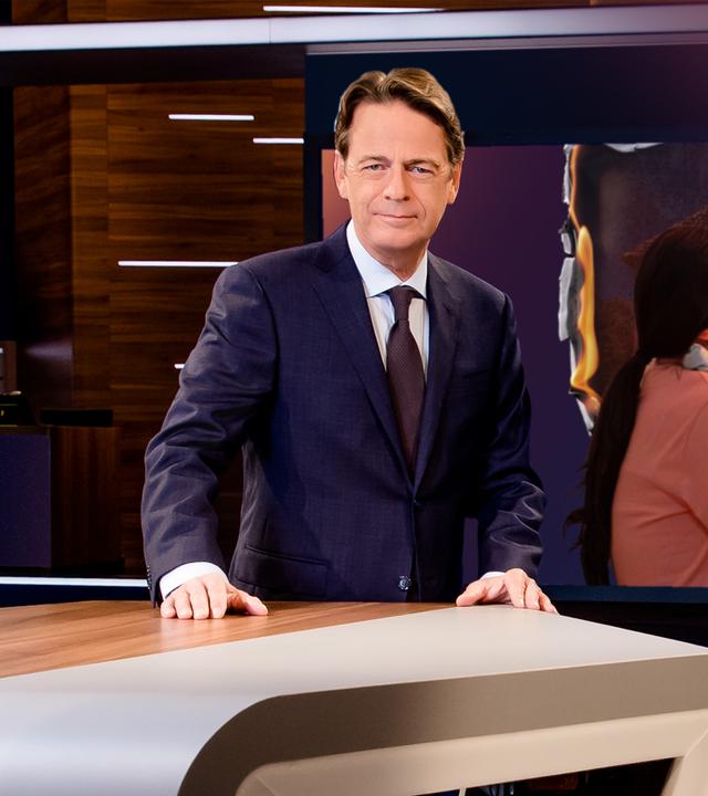 "Aktenzeichen XY... Ungelöst vom 06. Mai 2026": Rudi Cerne steht im Studio, im Hintergrund ein Bildschirm, auf dem ein Fall der Sendung abgebildet ist.