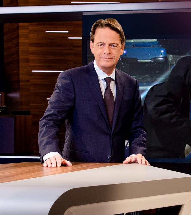 "Aktenzeichen XY... Ungelöst vom 03. Mai 2026": Rudi Cerne steht im Studio, im Hintergrund ein Bildschirm, auf dem ein Fall der Sendung abgebildet ist.