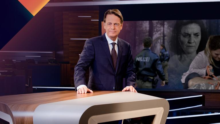 "Aktenzeichen XY... Gelöst vom 06. März 2024": Moderator Rudi Cerne steht im Studio, im Hintergrund ein Bildschirm, auf dem ein Fall der Sendung abgebildet ist.  
