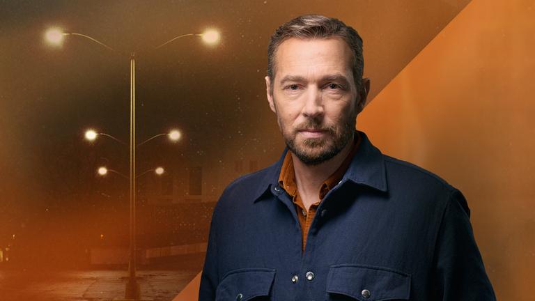 Eine Fotomontage mit Orange-Stich: Sven Voss im Vordergrund. Im Hintergrund eine leere Straße bei Nacht mit leuchtenden Straßenlaternen