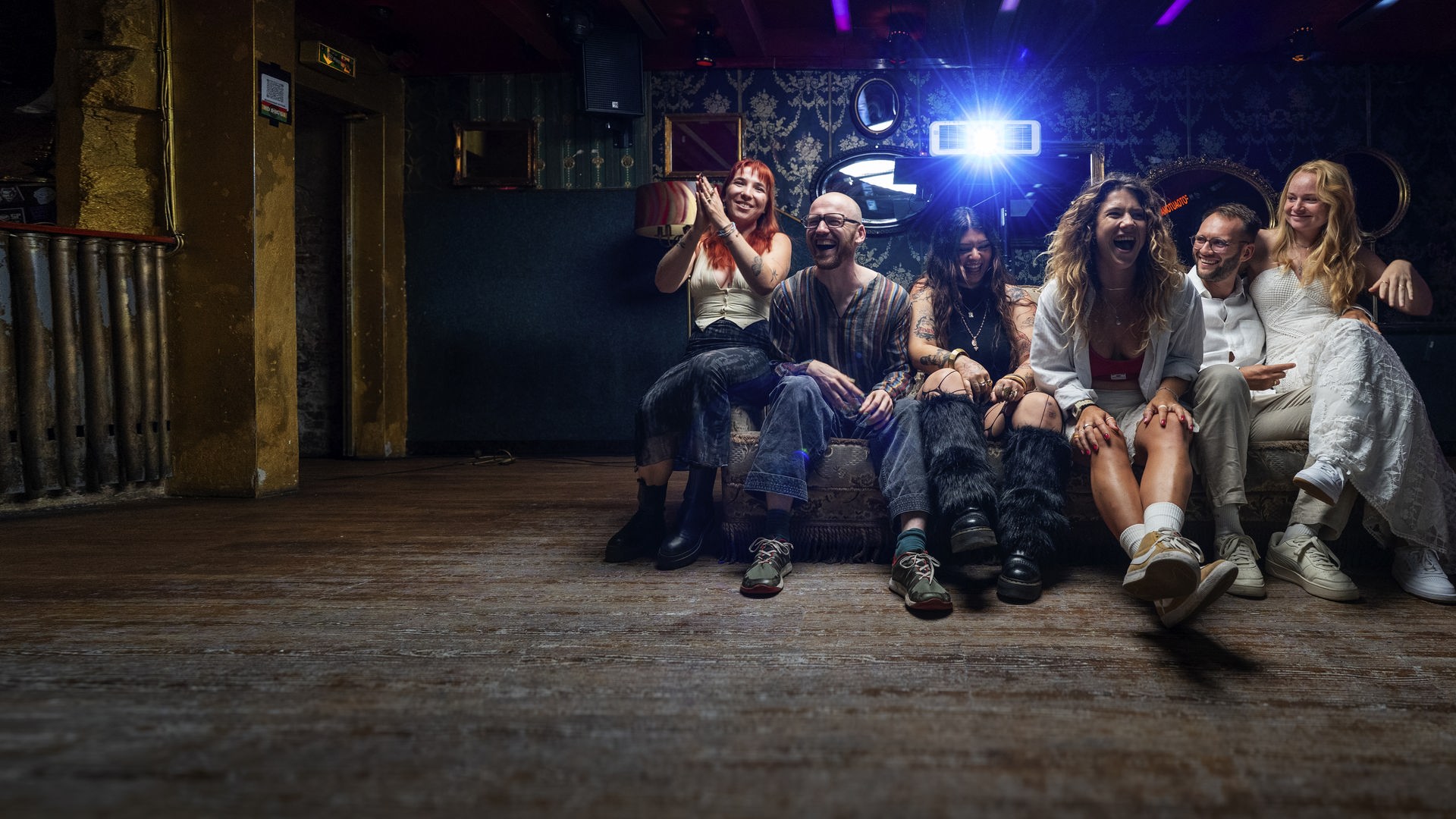  Janine, "Nine", Emmanuel "Emma", Defne, Yasmin "Yaz", Nico und Josephine "Jo" sitzen auf einem Sofa und lachen in die Kamera.