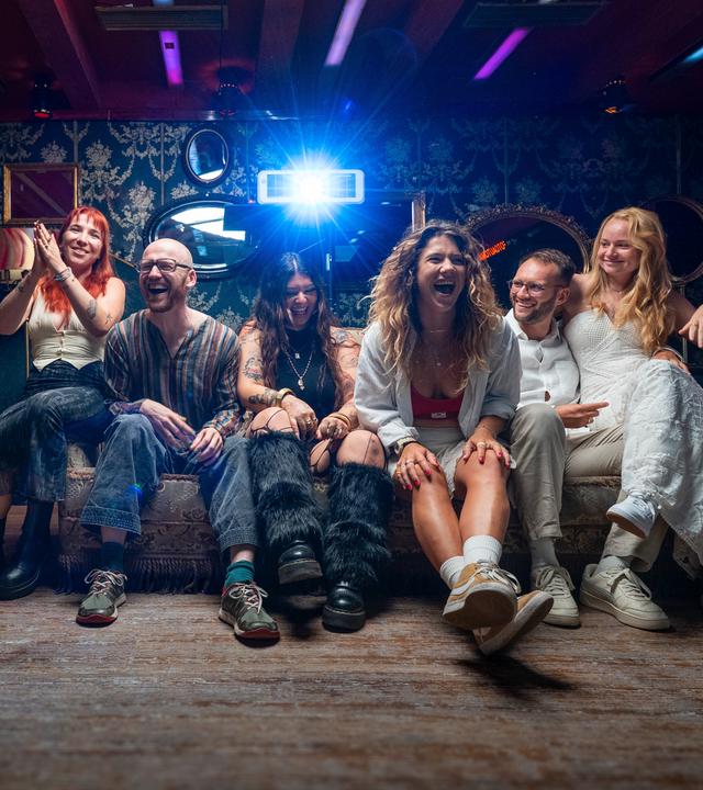 Janine "Nine", Emmanuel "Emma", Defne, Yasmin "Yaz", Nico und Josephine "Jo" sitzen auf einem Sofa und lachen in die Kamera.