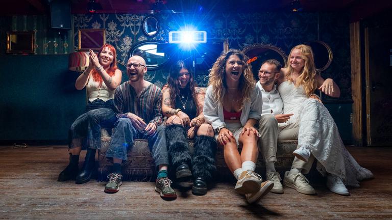 Janine "Nine", Emmanuel "Emma", Defne, Yasmin "Yaz", Nico und Josephine "Jo" sitzen auf einem Sofa und lachen in die Kamera.