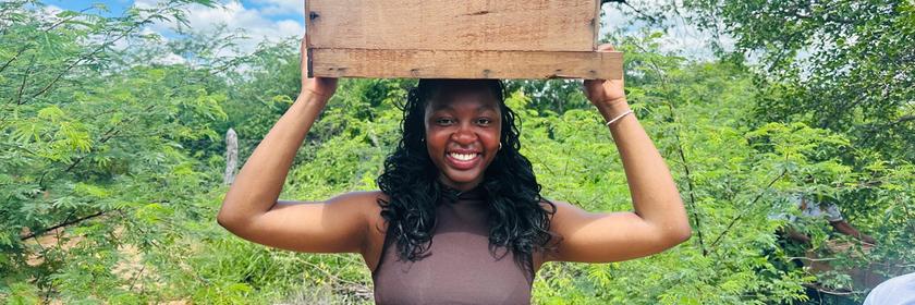 Auslandsjournal-Reporterin Sarah Danquah mit einem Bienenkasten auf dem Kopf bei einem Imker in Brasilien (Youtube-Kanal)