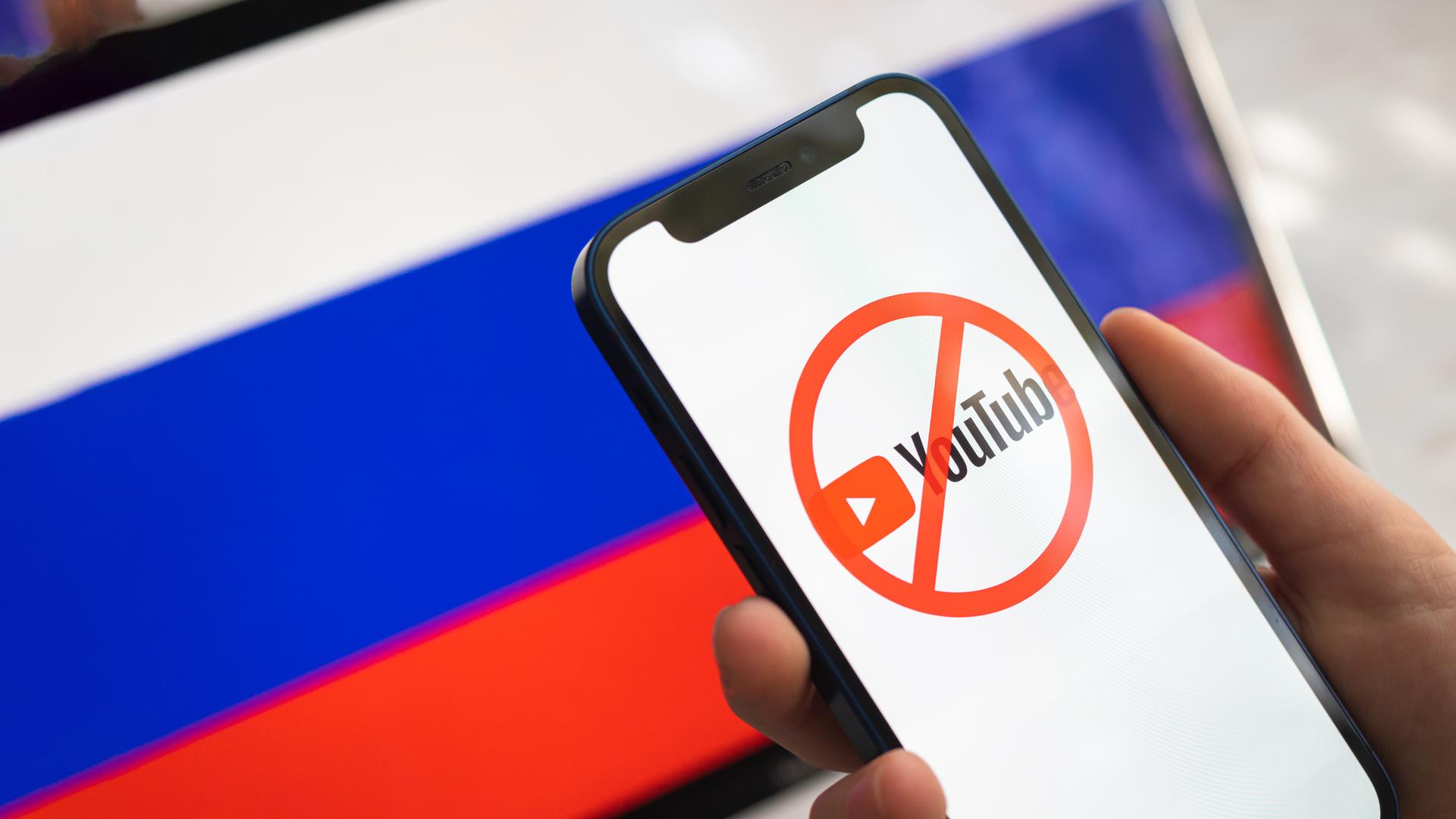 Smartphone mit gesperrtem Youtube-Logo vor Russland-Flagge