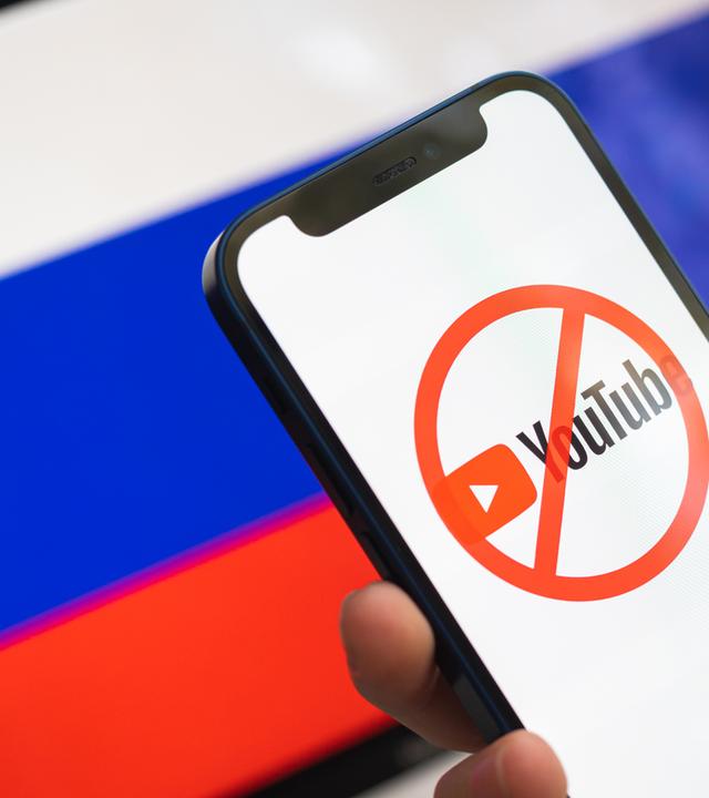Smartphone mit gesperrtem Youtube-Logo vor Russland-Flagge