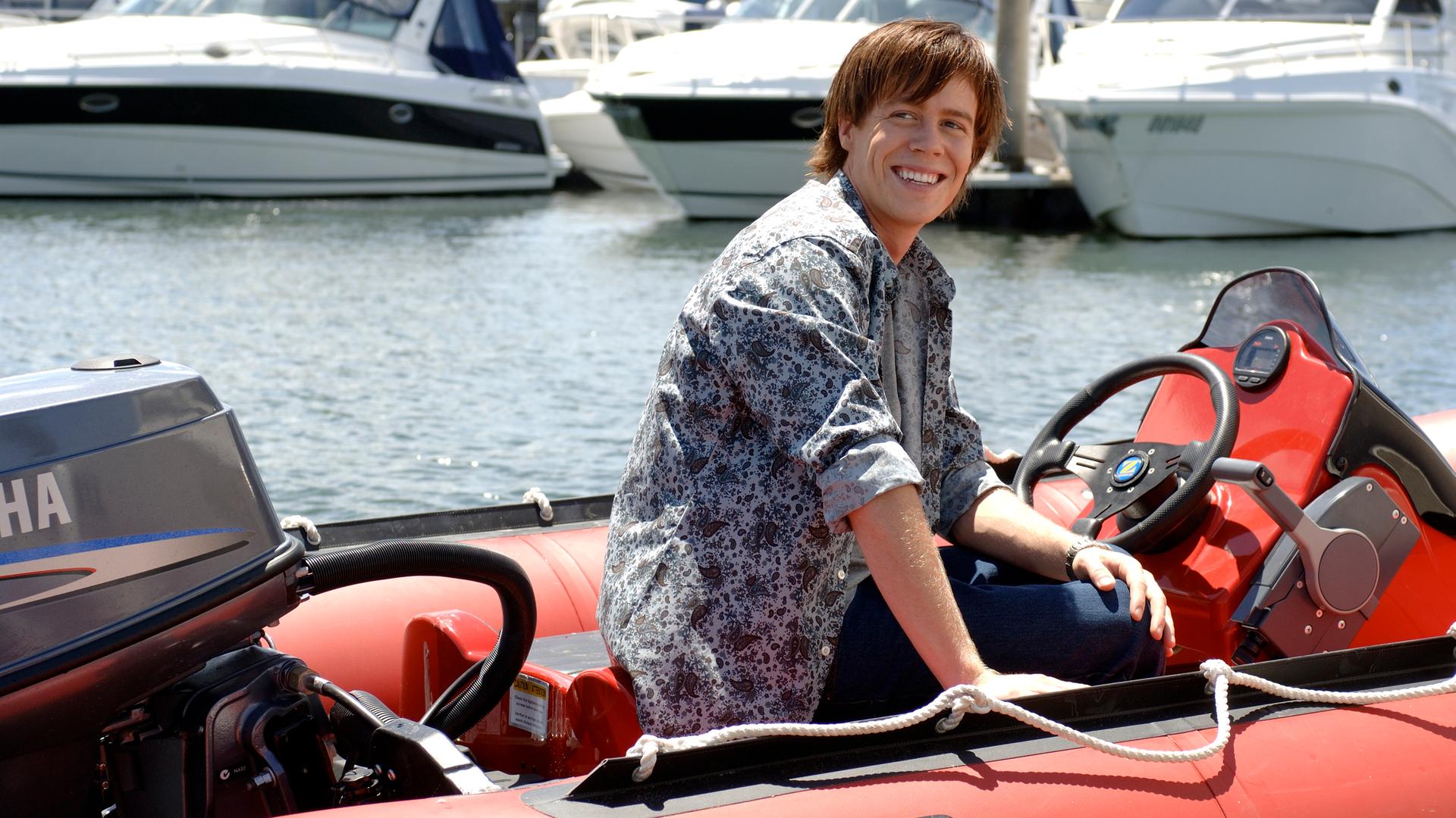 Zane sitzt in einem Schlauchboot und lächelt.