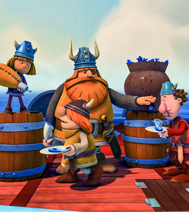 Die Wikiner stehen mit Tellern in der Hand an Bord des Schiffes, wo Halvar jedem einen Fisch austeilt. Wickie schenkt aus einem Schlauch Trinken ein. Alle sehen unglücklich aus.