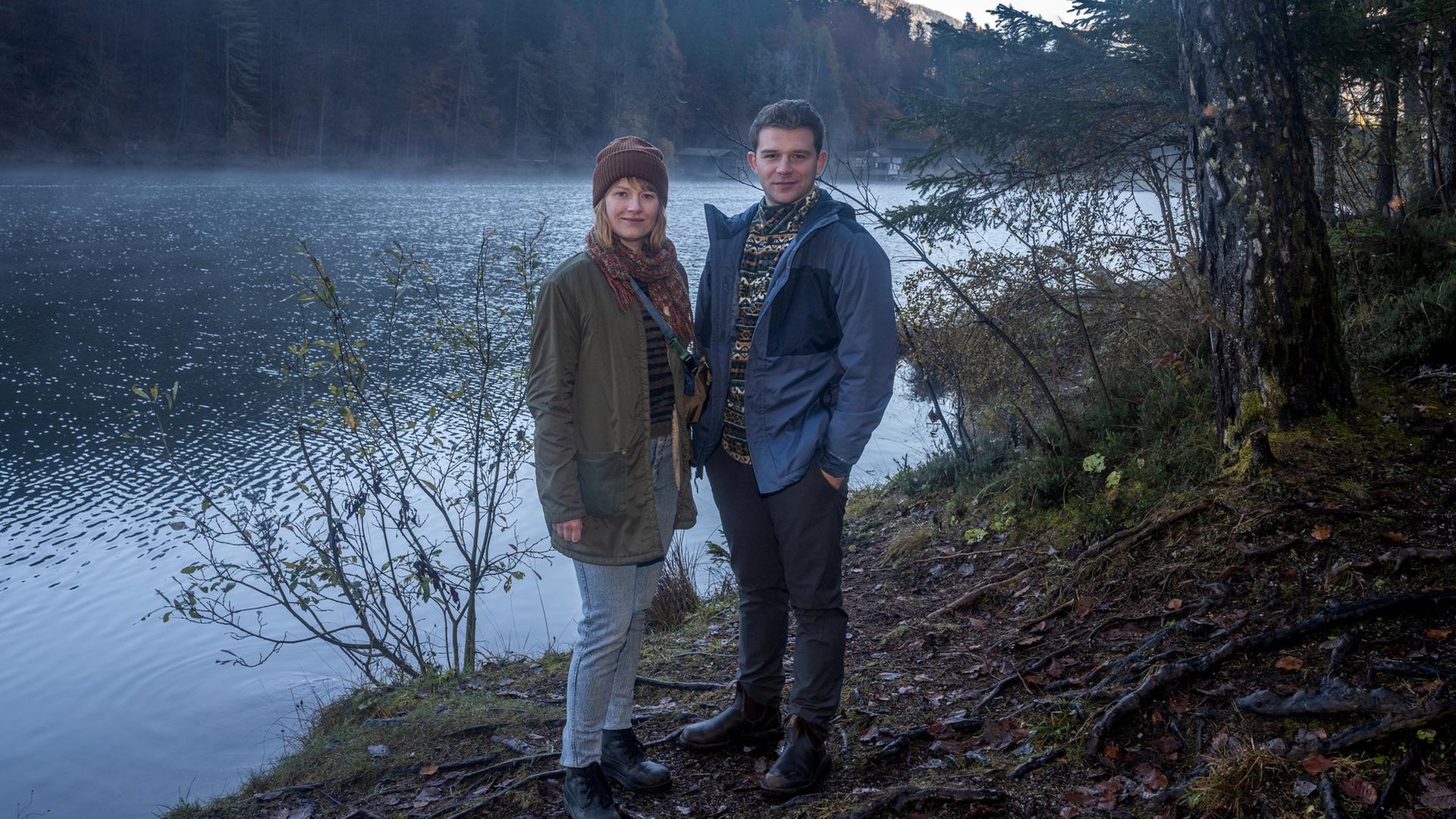 Schnee von Gestern - Landkrimi": Chefinspektorin Melanie Grandits (Marlene Hauser) und Chefinspektor Martin Steiner (Simon Morzé) stehen am Ufer.