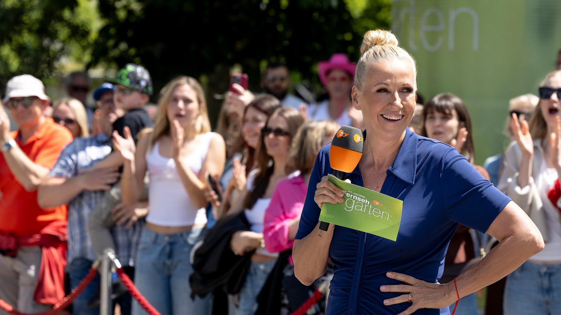 ZDF-Fernsehgarten-Moderatorin Andrea Kiewel mit Mikrofon vor einer Menschenmenge.