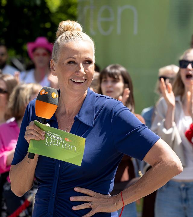 ZDF-Fernsehgarten-Moderatorin Andrea Kiewel mit Mikrofon vor einer Menschenmenge.