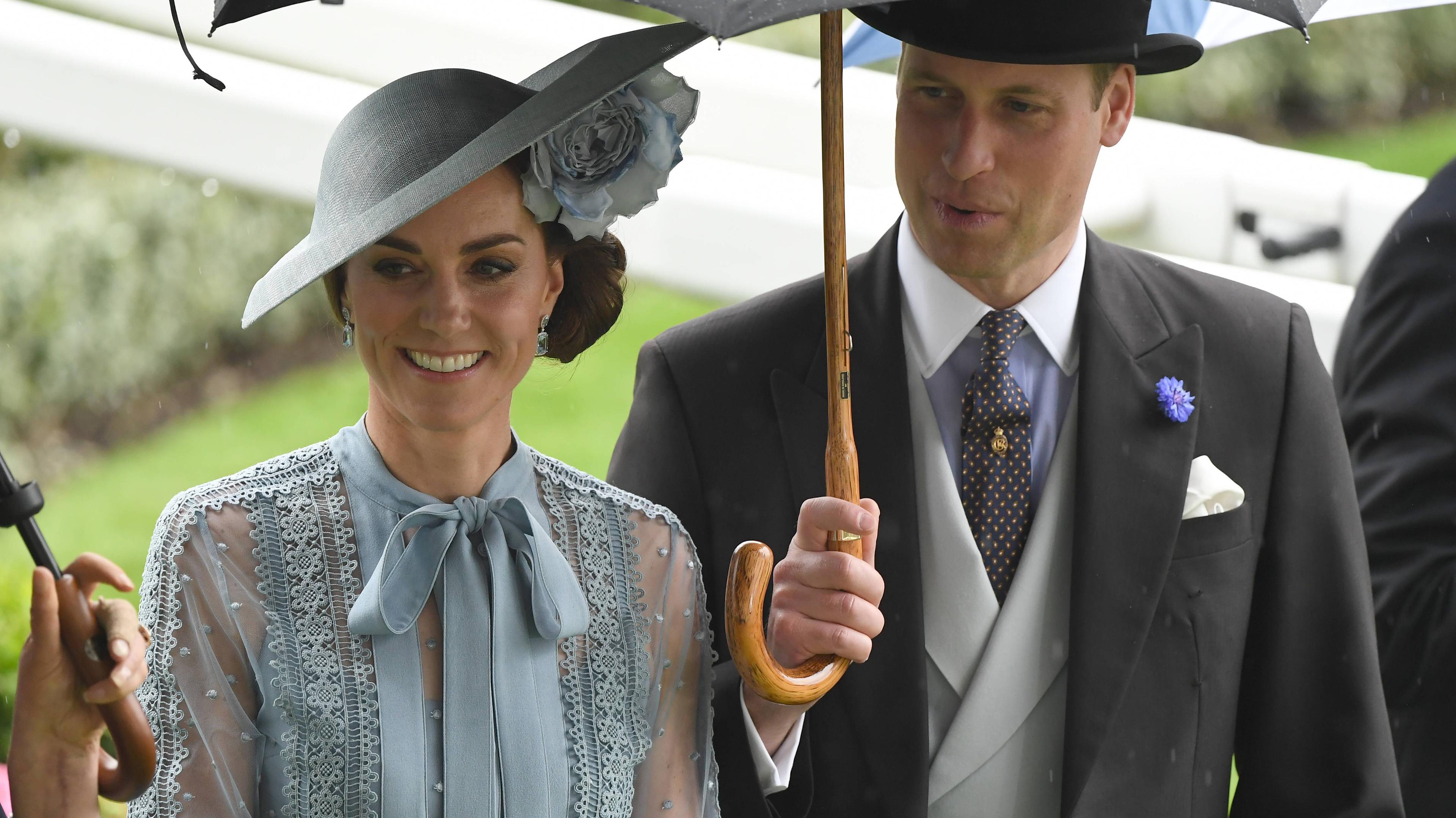 Kate und William von England unter einem Regenschirm.