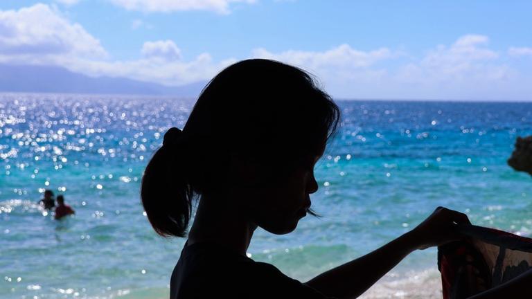 Kinderhilfe Philippinen: Gegenlicht-Nahaufnahme einer jungen Frau am Meer