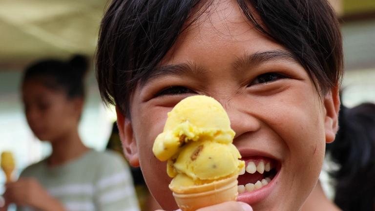 Kinderhilfe Philippinen: Ein kleiner Junge hält lachend ein Eis in die Kamera
