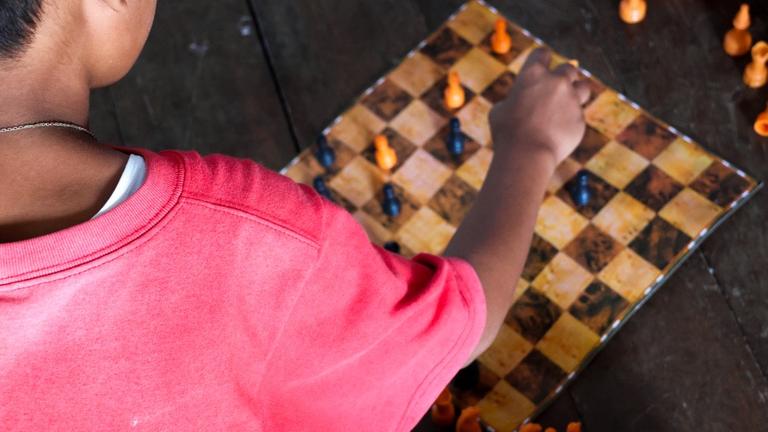 Kinderhilfe Philippinen: Ein Junge sitzt vor einem Schachbrett