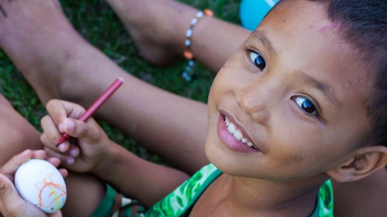 Kinderhilfe Philippinen: Ein kleiner Junge malt ein Osterei an