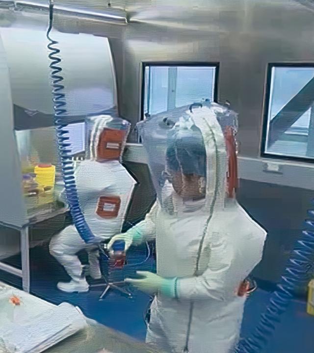 Drei Männer in Schutzkleidung befinden sich in einem Labor.