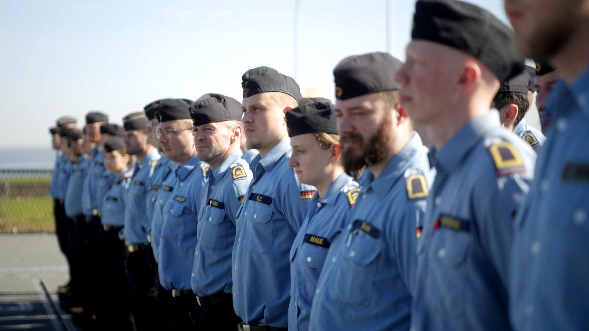Soldatinnen und Soldaten stehen auf einem Platz in einer Reihe.