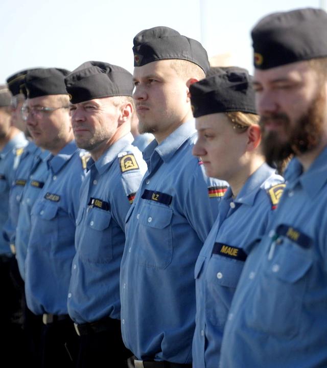 Soldatinnen und Soldaten stehen auf einem Platz in einer Reihe.