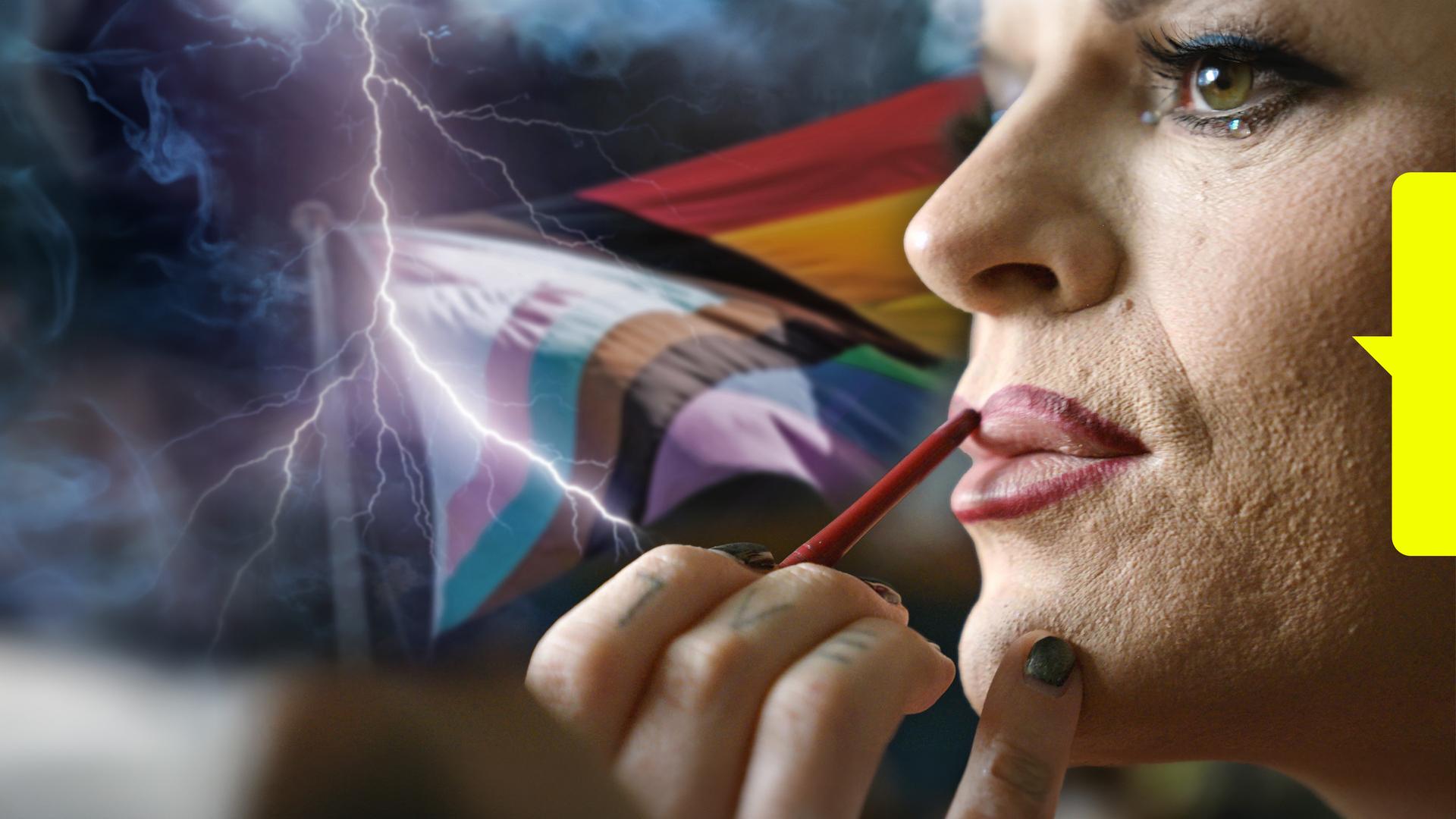 Nahaufnahme einer Person, deren Lippen mit einem roten Stift konturiert werdne. Im Hintergrund sind verschiende Pride-Flaggen zu sehen.