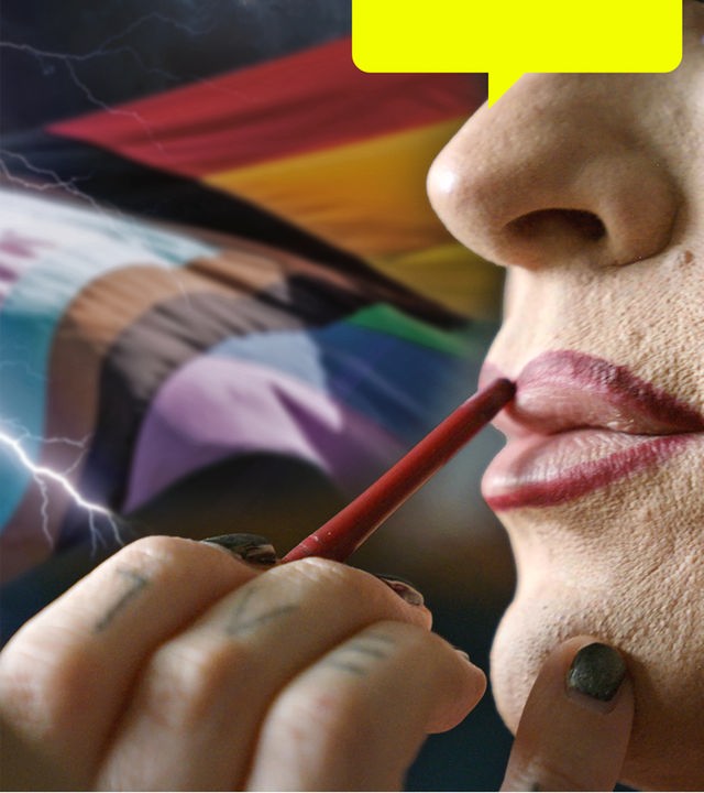 Nahaufnahme einer Person, deren Lippen mit einem roten Stift konturiert werdne. Im Hintergrund sind verschiende Pride-Flaggen zu sehen.