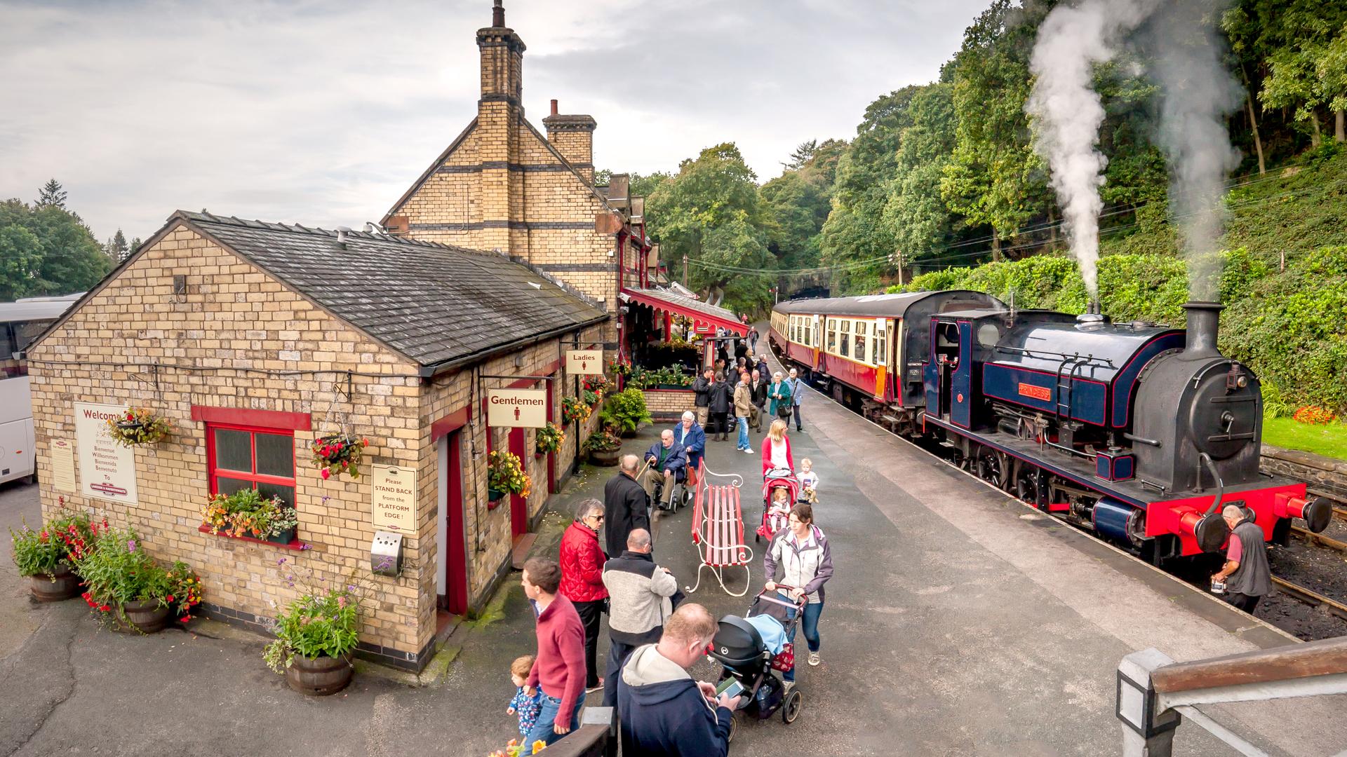Menschen warten an der Haverthwaite Station in England auf den Zug.