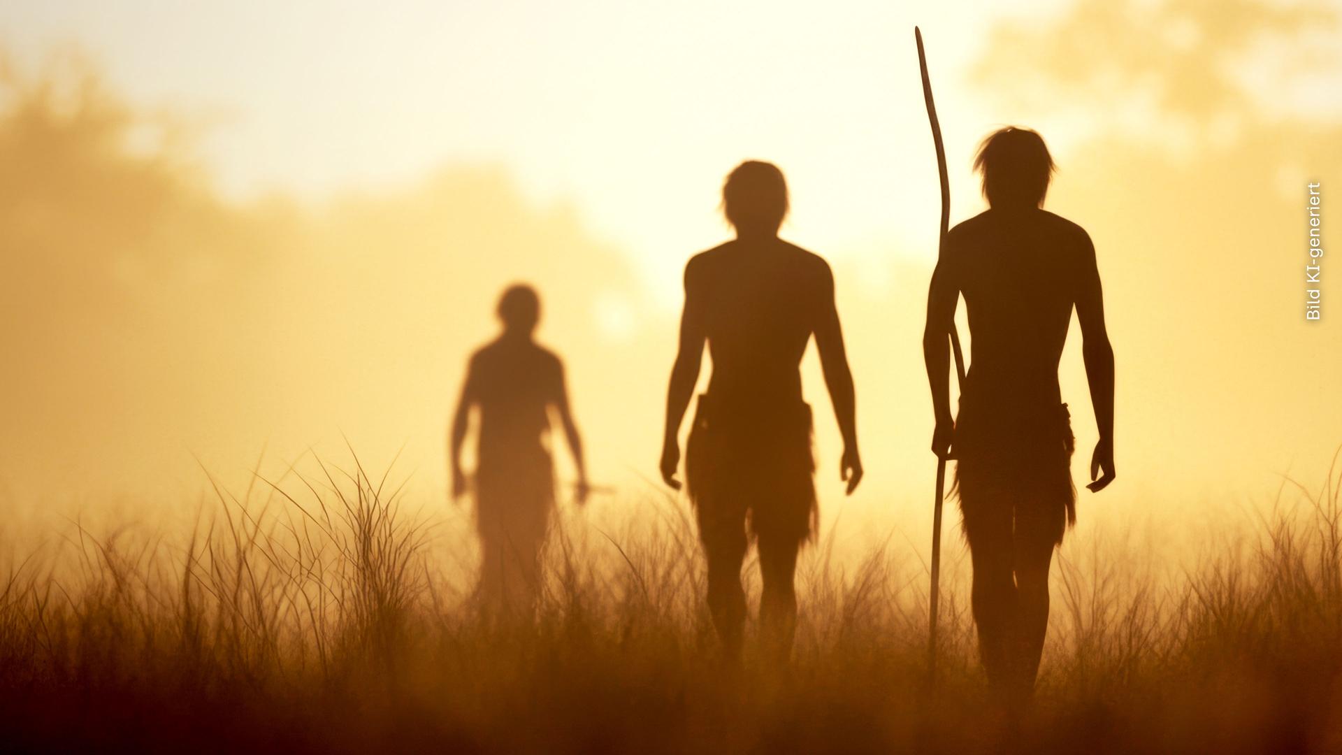 Eine Gruppe Urzeitmenschen in der Steppe, im Gegenlicht sind nur ihre Konturen zu erkennen